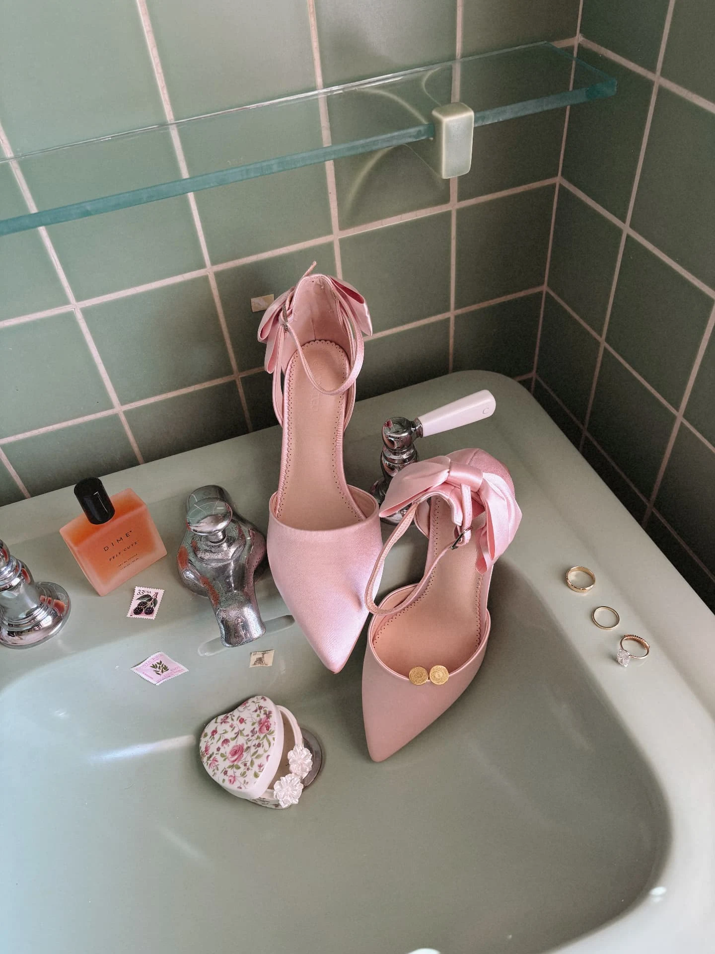 Pink bridal heels and wedding details arranged on a tiled vanity