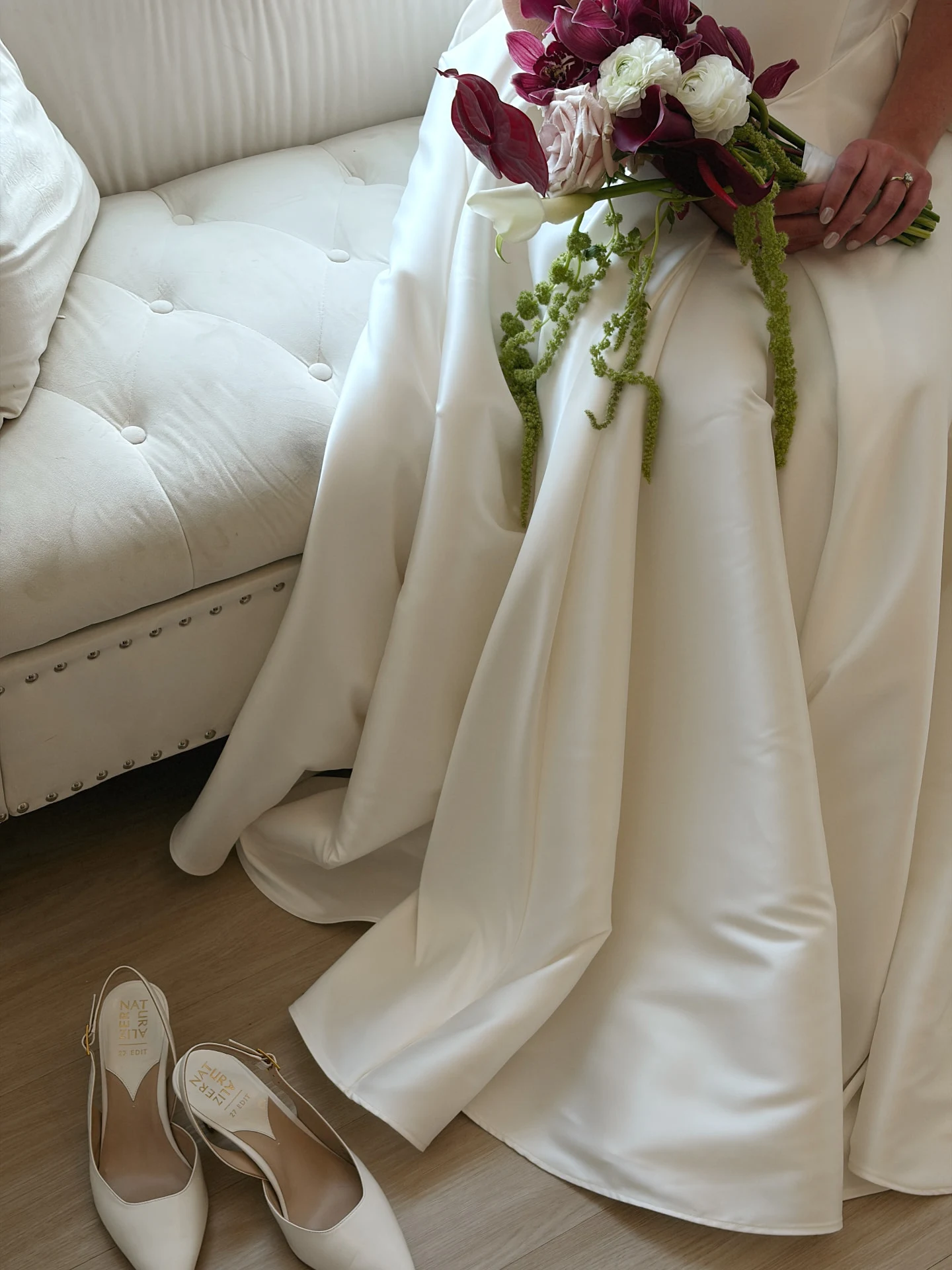 Bride holding a burgundy and white bouquet above her flowing wedding dress