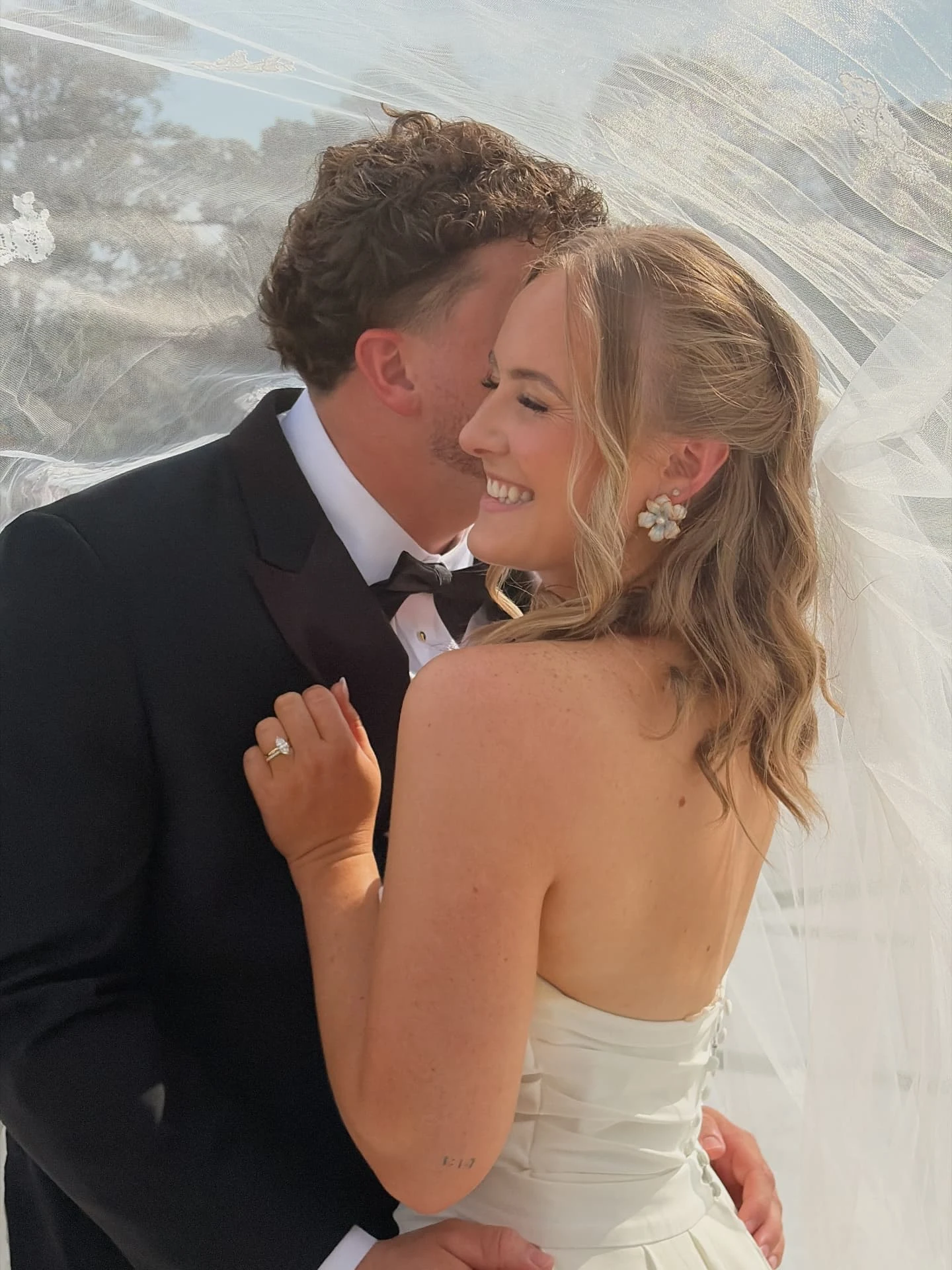 Groom kissing the smiling bride beneath her veil